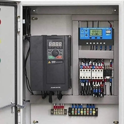 An open electrical control panel containing a large black inverter drive, a blue solar charge system controller, and multiple fuses and terminal blocks on a gray metal cabinet.